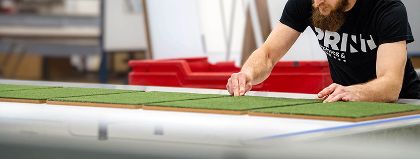 print operator working with game boards on a flatbed printer.