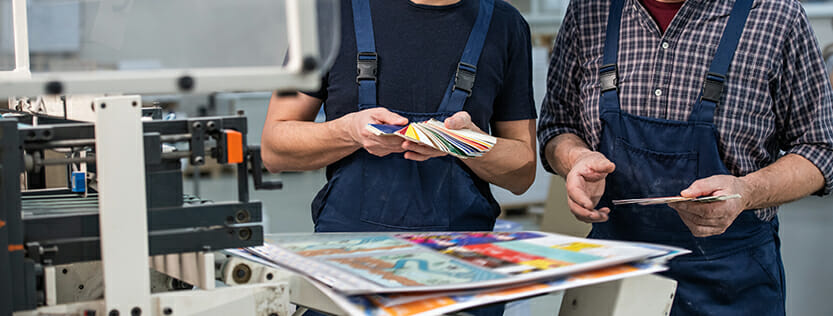Two men looking at color samples at a print shop.
