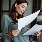 Young woman reading from 2 sheets of paper she is holding