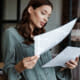 Young woman reading from 2 sheets of paper she is holding