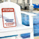 Lifeguard char beside pool with No Lifeguard on Duty warning sign