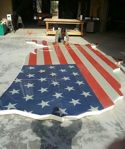 Print professional in precision cutting at PRI Graphics working on a print of a large American flag