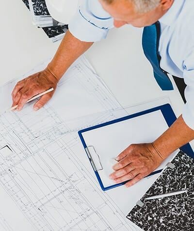 Man standing at a desk looking over an architectural drawing