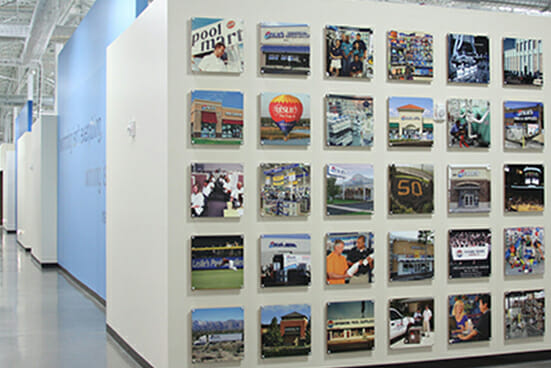 A wall with 30 color photos mounted on it.