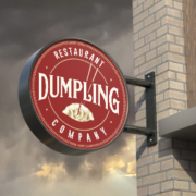 Round printed wall-mounted signage for Dumpling restaurant.