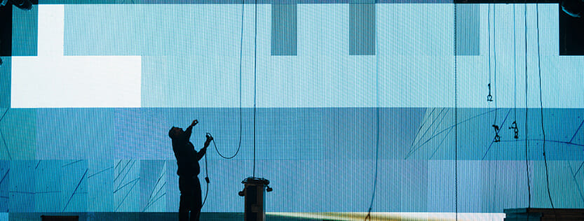silhouette of man hanging signage at event using ropes and wire
