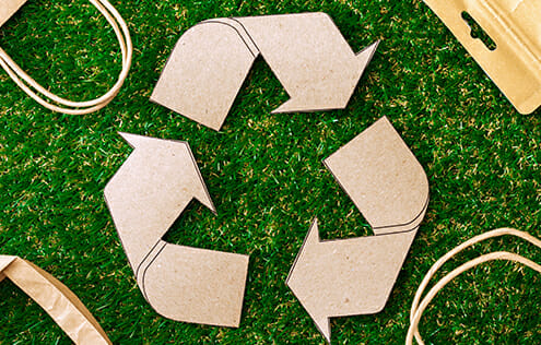 Recycle logo surrounded by different paper products.