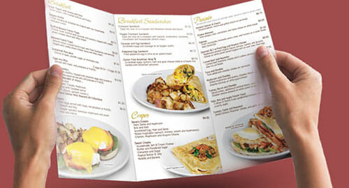 Hands holding a trifold breakfast menu.