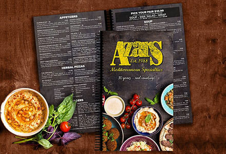 Spiral-bound restaurant menus on a wooden table.