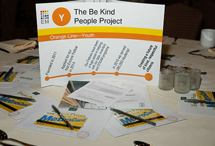 Upright-standing presentation display with various paper forms scattered around it.