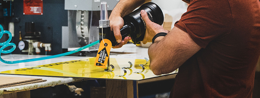 man using a power tool on safety signage.